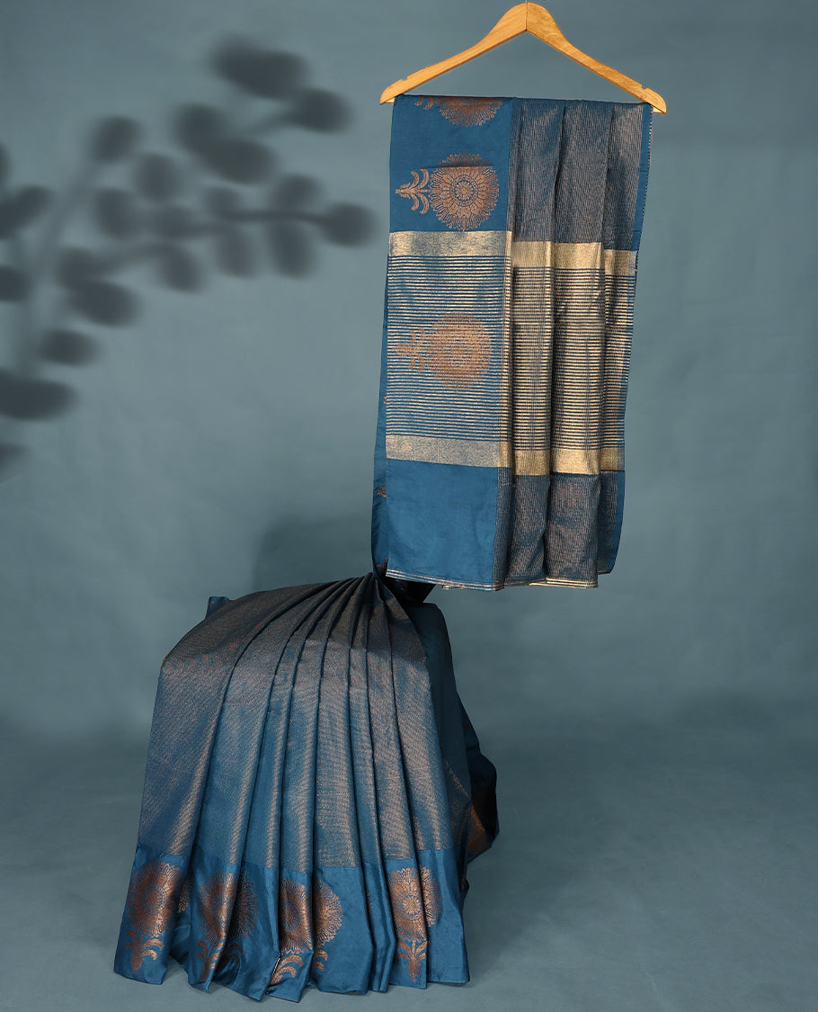Blue Colour Semi Tussar Silk saree featuring golden zari horizontal lines across the body, adorned with bold floral motifs on the border, paired with a matching blouse.