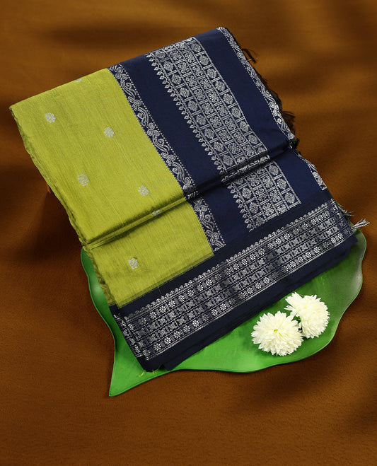 Lemon Green colour mixed Kalyani cotton saree featuring Silver zari Flower motifs throughout the body, paired with a Deep Navy Blue colour traditional border and pallu, with matching blouse