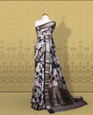 Grey colour saree adorned with bold black floral prints and a rich black zari border and stripped checkered pallu & Comes with a matching blouse piece.