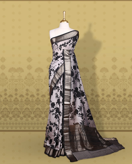Grey colour saree adorned with bold black floral prints and a rich black zari border and stripped checkered pallu & Comes with a matching blouse piece.