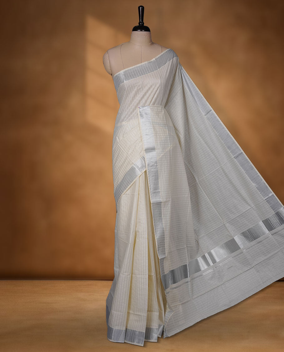 Off-white colour cotton Kerala saree featuring a silver line pattern, finished with an elegant silver kasavu border along the edges and pallu, and paired with a matching blouse.