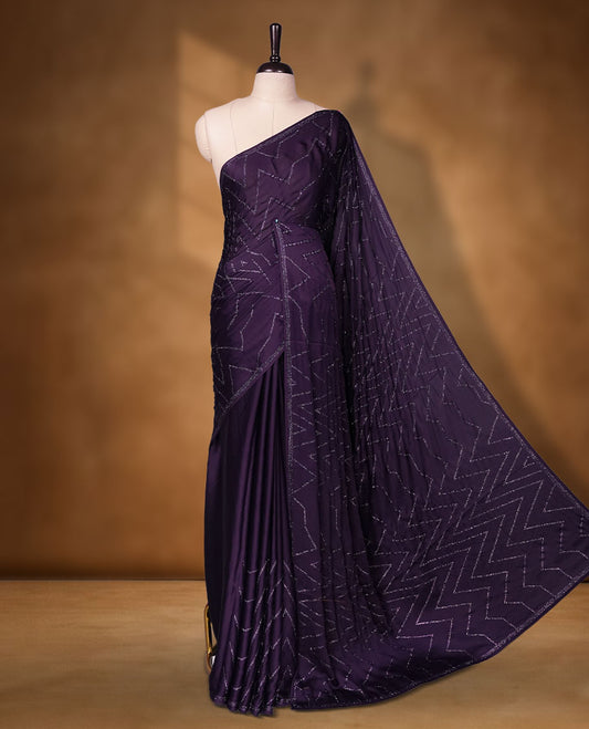 Dark violet Colour shimmer fancy saree adorned with red stone buttas all over the body, paired with a delicate stone worked border and matching blouse featuring floral vine stone embroidery