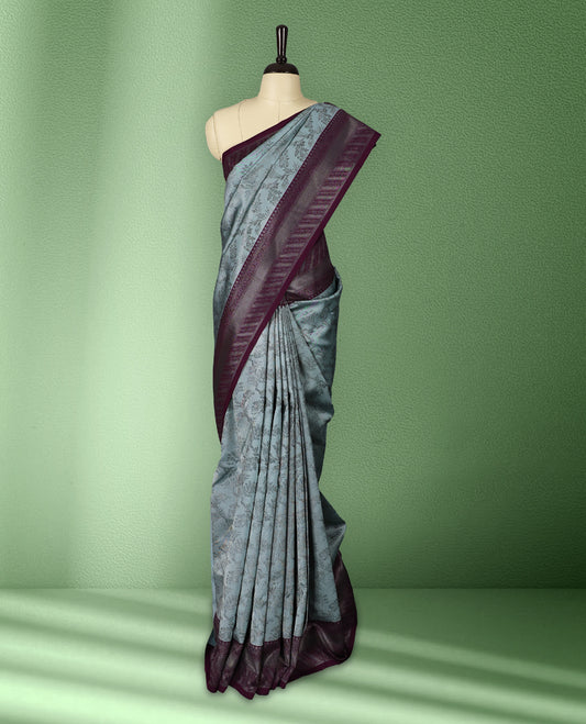 Pastel blue colour semi silk saree featuring neem zari floral kodi motifs all over the body, complemented by a rich royal purple woven border with geometric detailing, with matching blouse.