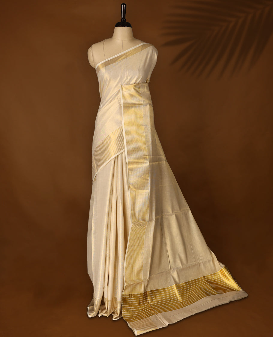 Elegant Light Gold colour Tissue Kerala saree featuring Plain body and traditional golden zari kasavu 5 Inch border  with White stripes offering a classic and graceful look, paired with a matching blouse.