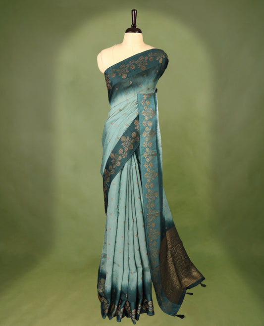 Sea green and teal double shade semi Banaras Tussar Georgette saree adorned with elegant antique gold zari floral motifs across the body, featuring a detailed woven border and grand pallu, paired with a matching blouse piece.