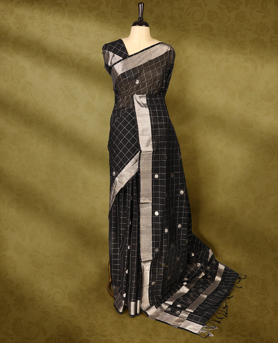 Black colour pure handloom cotton kerala saree with white checkered pattern and silver woven buttas on the body, silver zari border, pallu detailed with silver zari stripes and buttas, with matching blouse
