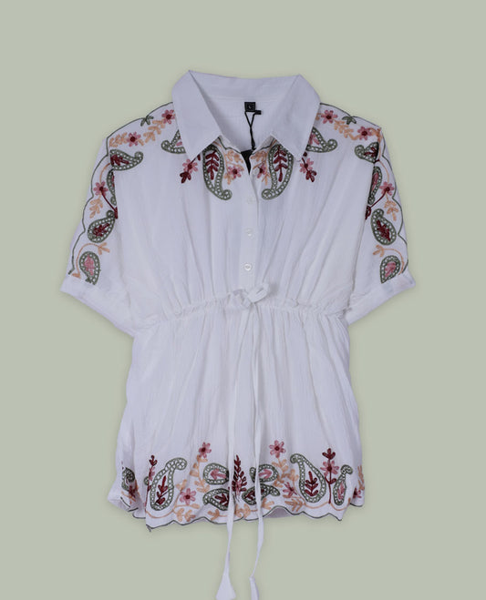 White short tunic top with collared neckline, short sleeves, multicolour paisley and floral embroidery on shoulders and hem, and a drawstring waist with long tasseled ties.