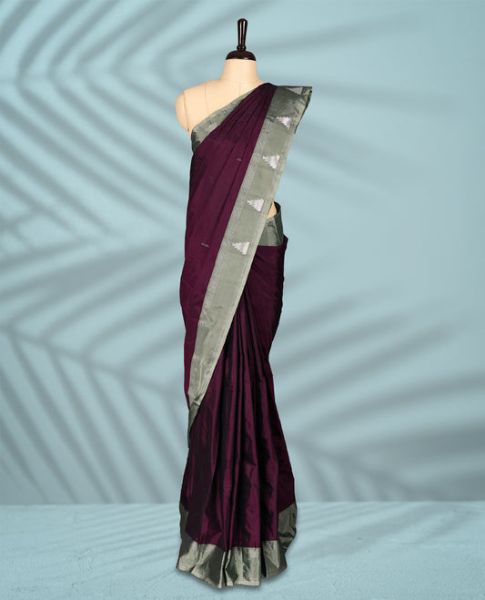 Burgundy Colour semi silk saree features an all over silver zari pattern and a sage green border adorned with traditional temple motifs, paired with a matching blouse.