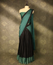 Black colour semi-stitched traditional half saree in semi Banarasi silk, featuring a checked design with a dark Pastel green bordered skirt. It is paired with a Rangoli georgette drape and comes with a blouse that matches the skirt’s border.