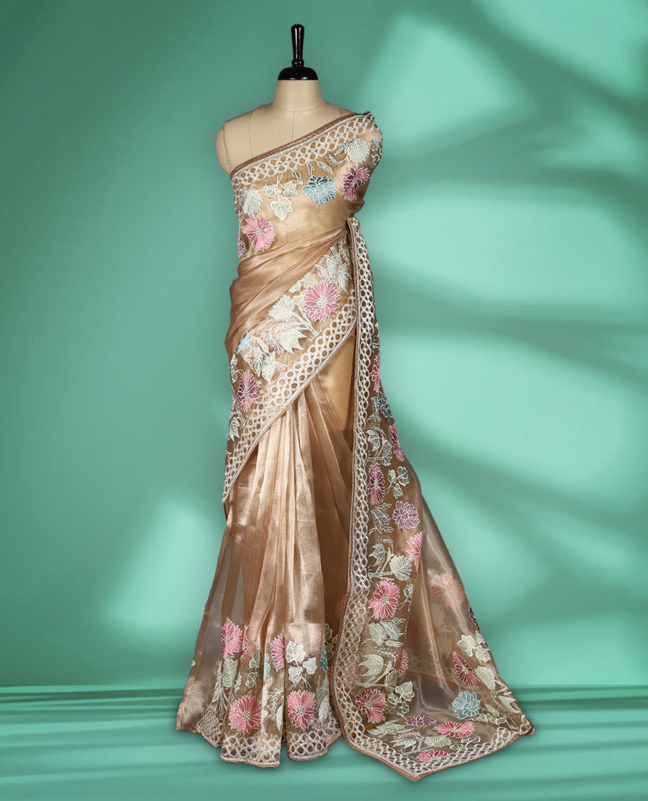Light Brown colour organza designer saree featuring delicate pastel floral embroidery in pink, mint green, and white across the body, with a scalloped border accentuated by floral threadwork, and a gracefully embroidered pallu paired with matching blouse.