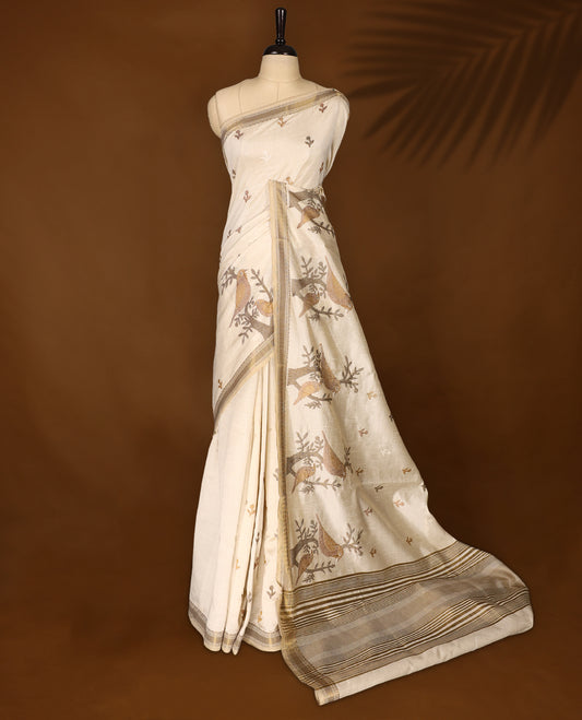 Soft Tussar saree in elegant off white shade, featuring intricate bird and branch motifs across the body, enhanced with a subtle grey golden woven border and pallu, paired with a matching blouse.
