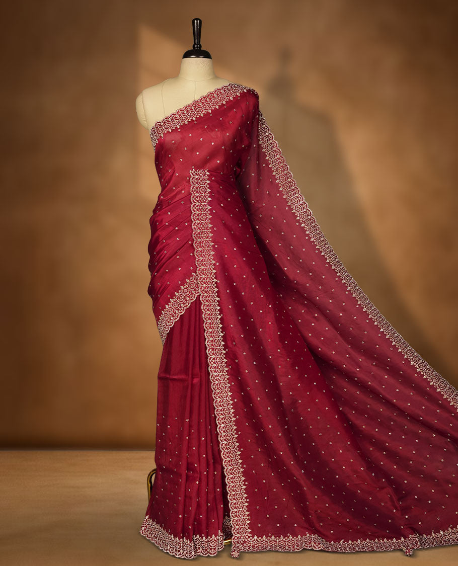 Dark Magenta Colour net shimmer fancy saree adorned with scattered white stone buttas all over the body, paired with a delicate stone worked border and matching blouse featuring floral vine stone embroidery