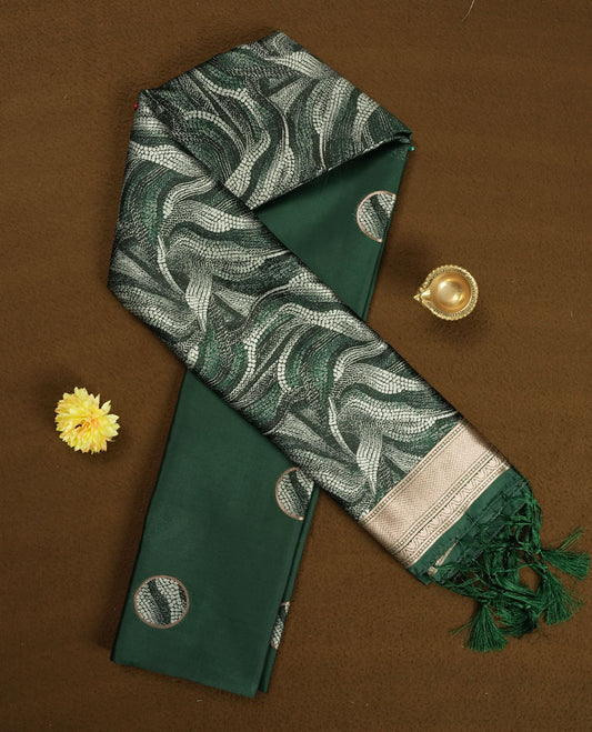 Dark green semi silk saree featuring elegant circular motifs on the body, complemented by a striking pallu adorned with intricate wavy silver thread patterns, and paired with a matching blouse