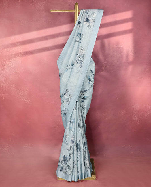 Soothing sky blue colour pure linen saree adorned with delicate floral digital prints across the body, finished with a plain matching border and pairs beautifully with a coordinated blouse.