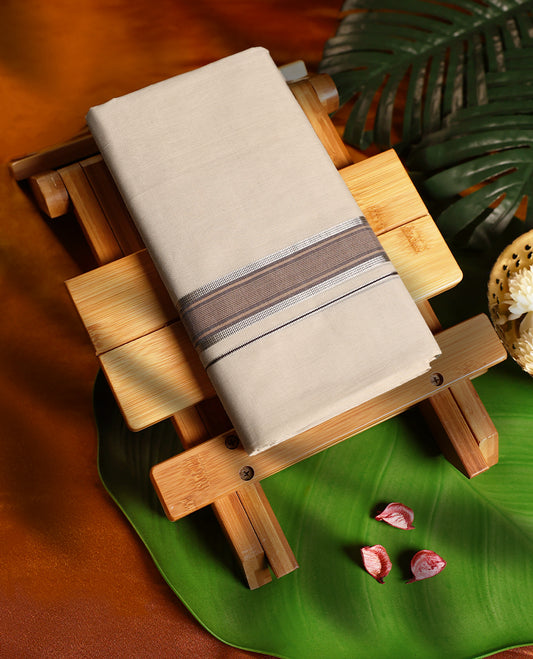 Off white colour pure handloom cotton double dhoti featuring an elegant pastel brown kara with silver lining, crafted with traditional finesse and designed for festive occasions, rituals, and everyday elegance.