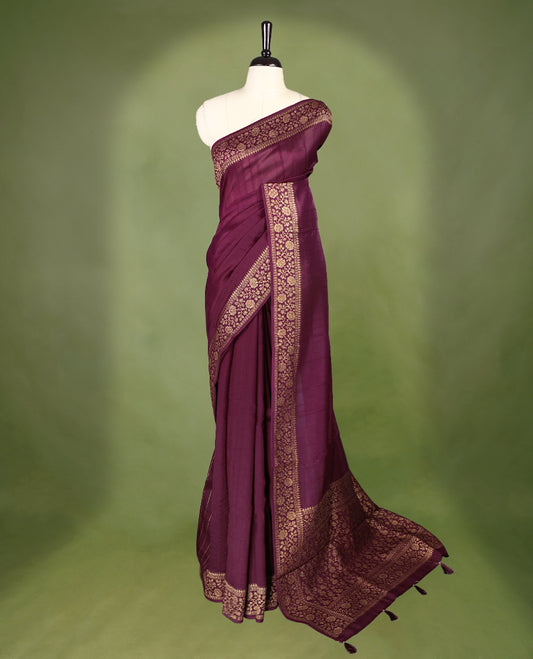 Maroon colour Tussar Banaras saree featuring a plain body, rich floral woven zari border and grand pallu, paired with a matching blouse for an elegant and regal traditional look.