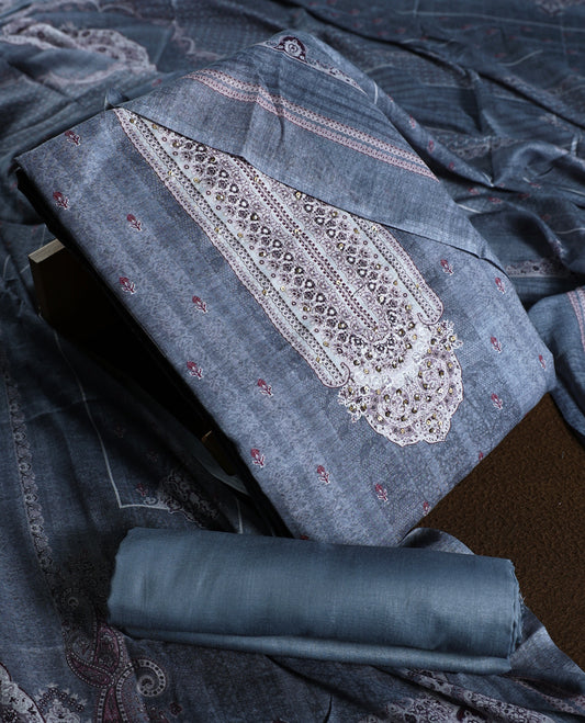 Denim blue colour churidhar material with intricate white and silver embroidery on the neckline, paired with a coordinated printed dupatta and plain bottom.