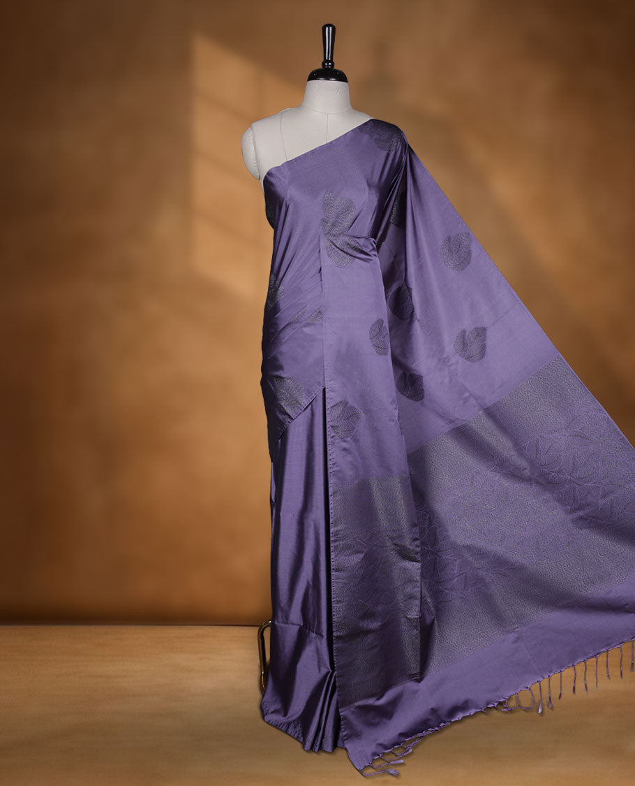 Pastel purple colour semi soft silk saree adorned with delicate woven floral kodi motifs on the body, complemented by a Self colour woven pallu with intricate detailing and tassel accents without border & Comes with a matching blouse piece.