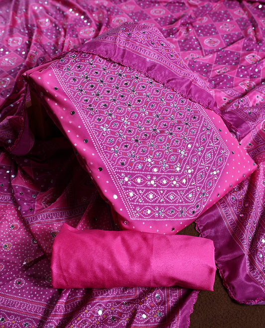 Magenta colour churidhar material adorned with intricate bandhani patterns and sparkling mirror work, paired with a plain matching bottom and elegant dupatta, perfect for festive gatherings and traditional celebrations.