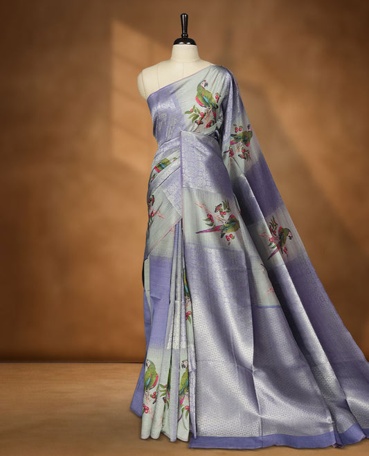 Gray Blue colour semi tussar Banarasi saree featuring printed parrot and floral motifs, gray blue zari border, and a matching blouse with woven accents.