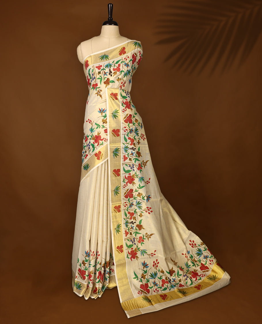 Elegent Off white colour cotton Kerala saree featuring vibrant multicolor floral prints all over the body, beautifully highlighted with a rich golden zari border paired with matching blouse.
