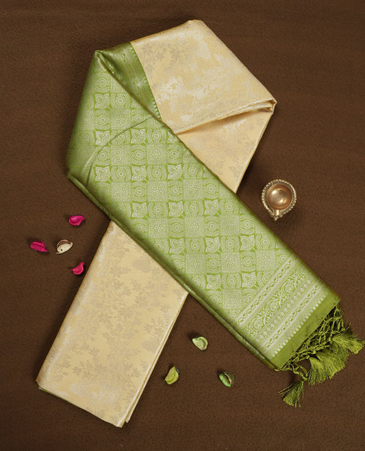 Light cream colour semi silk saree adorned with delicate golden zari buttas across the body, complemented by an elegant olive green pallu and matching border, and paired with a coordinated blouse piece