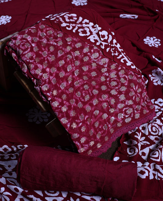 Red wine colour churidhar material adorned with gold and copper toned floral patterns and bold block designs, paired with a plain matching bottom and stylish dupatta, perfect for festive evenings and traditional gatherings.