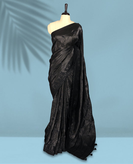 Black Colour crush soft silk saree boasts a lustrous crinkled texture with subtle self colored floral Motifs on the body and an elegant Floral thread cutwork border, paired with a matching blouse.
