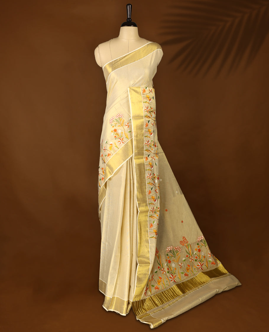 Light Gold colour Tissue Kerala saree featuring Orange and white Colour Floral thread work on body and a beautifully woven Gold Kasavu border, paired with a matching blouse perfect for festive occasions.