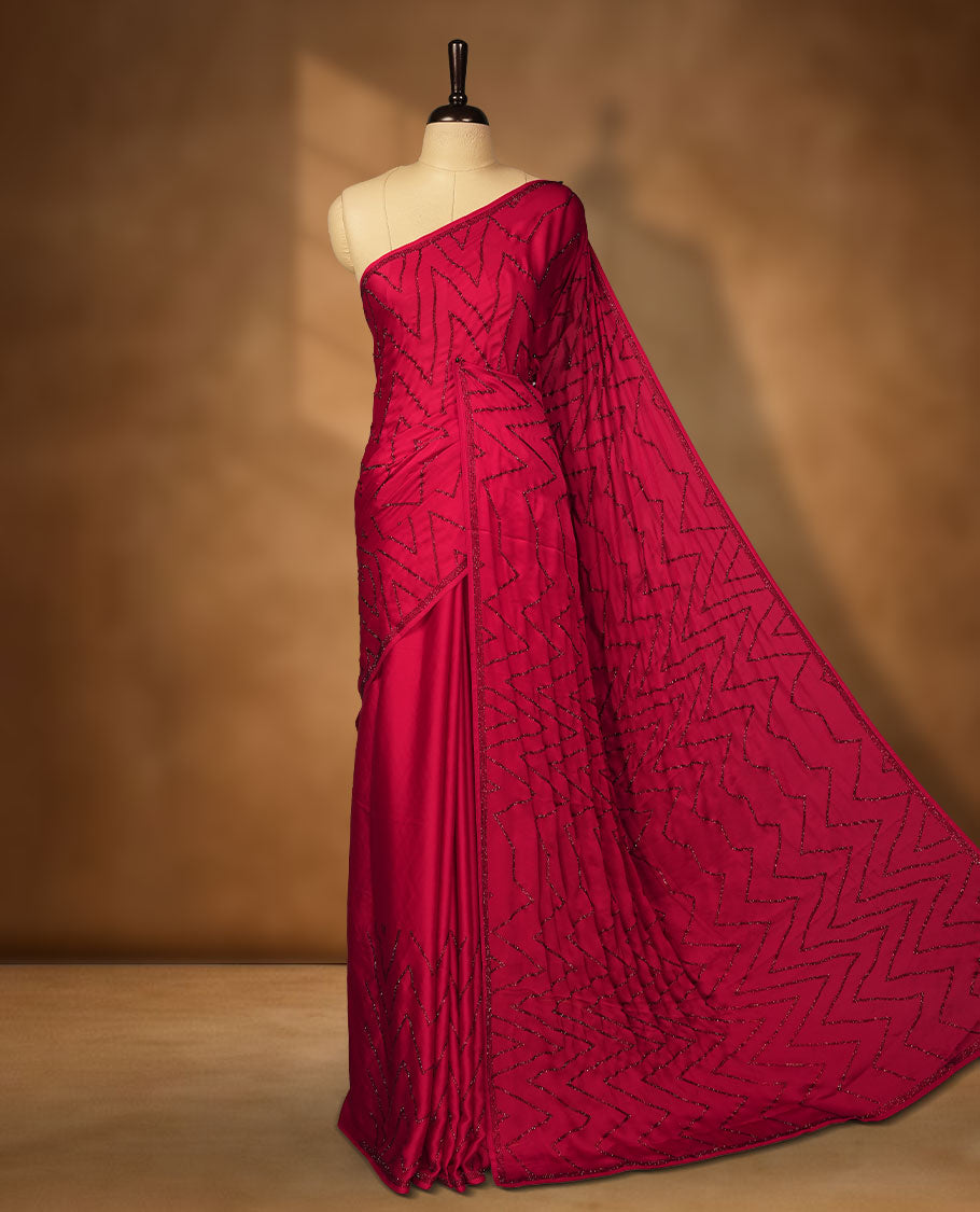 Dark Red Colour net shimmer fancy saree adorned with red stone buttas all over the body, paired with a delicate stone worked border and matching blouse featuring floral vine stone embroidery.