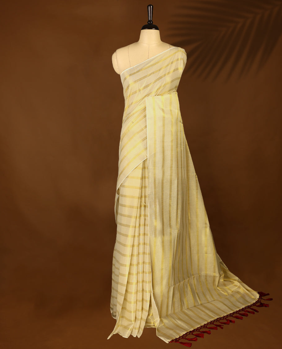 Light Gold colour Tissue Kerala saree featuring Gold zari Striped body, with Maroon colour tassels with a matching blouse perfect for festive occasions.