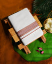 Off white colour cotton dhoti adorned with a rich rust brown kara and fine gold accents & crafted for heritage elegance and everyday ease, perfect for rituals, festive gatherings, and cultural events.