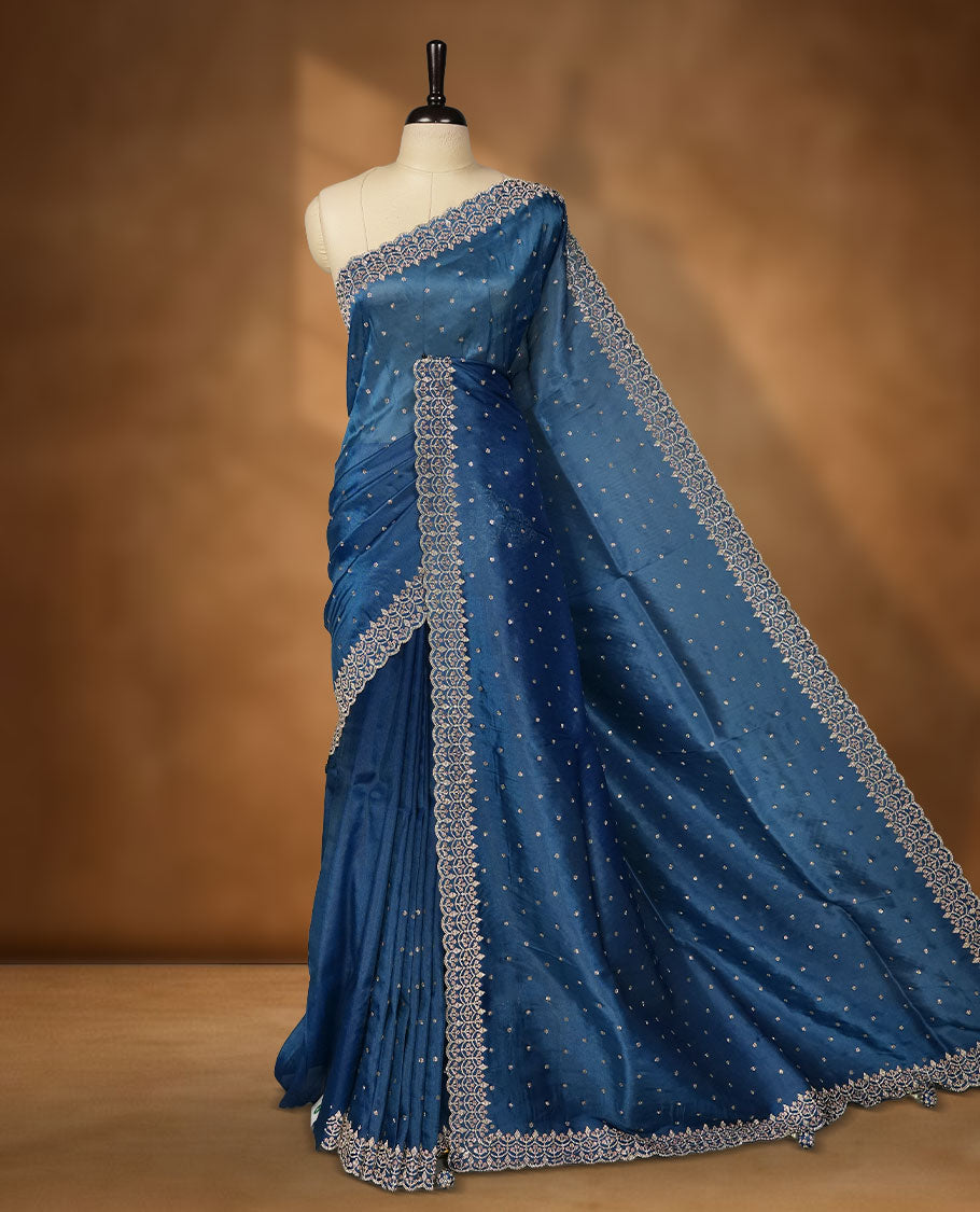 Blue colour net shimmer fancy saree adorned with white stone buttas all over the body, paired with a delicate stone worked border, with matching blouse