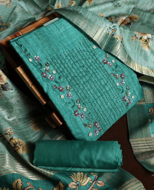 Light peacock green colour churidhar material adorned with floral embroidery and sewn glass beads on the yoke, paired with a plain green bottom and a beige dupatta featuring floral prints.