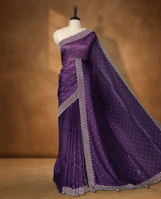 Dark Purple Colour net shimmer fancy saree adorned with scattered white stone buttas all over the body, paired with a delicate stone worked border and matching blouse featuring floral vine stone embroidery (Copy)
