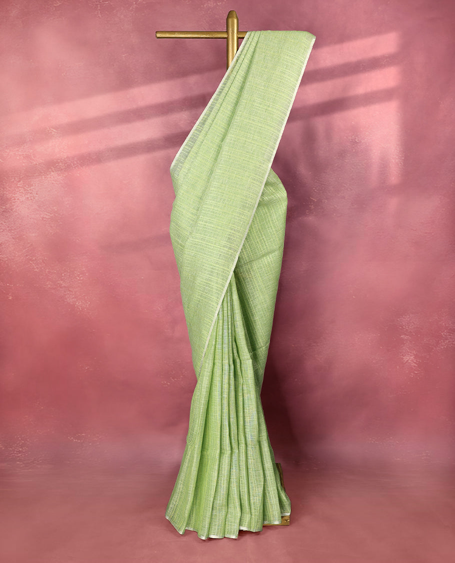 Pastel green colour pure linen saree adorned with delicate stripe patterns all over the body, highlighted with a simple white border and comes with a matching blouse