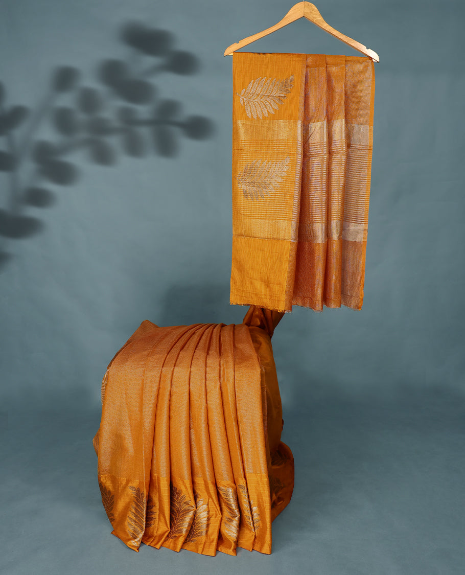 Mustard Colour Semi Tussar Silk saree featuring golden zari horizontal lines across the body, adorned with bold Leaf motifs on the border, paired with a matching blouse.
