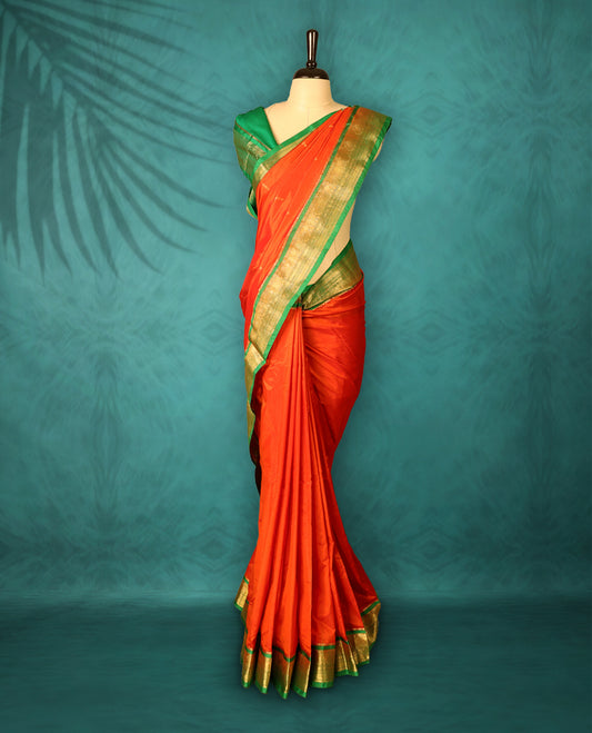 Deep Orange colour Traditional Kancheepuram Silk saree with small gold motifs on body, Green traditional border with intricate gold zari weaving, grand zari pallu, perfect for Bharatanatyam, with matching blouse.