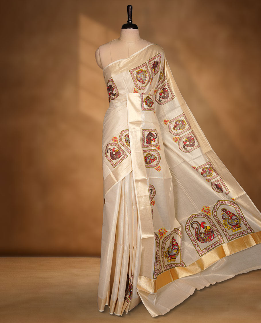 Off-white colour tissue Kerala saree, featuring a rich gold kasavu border and traditional Kalamkari-inspired peacock and elephant motifs across the body and pallu. Lightweight, breathable, and paired with a matching blouse.