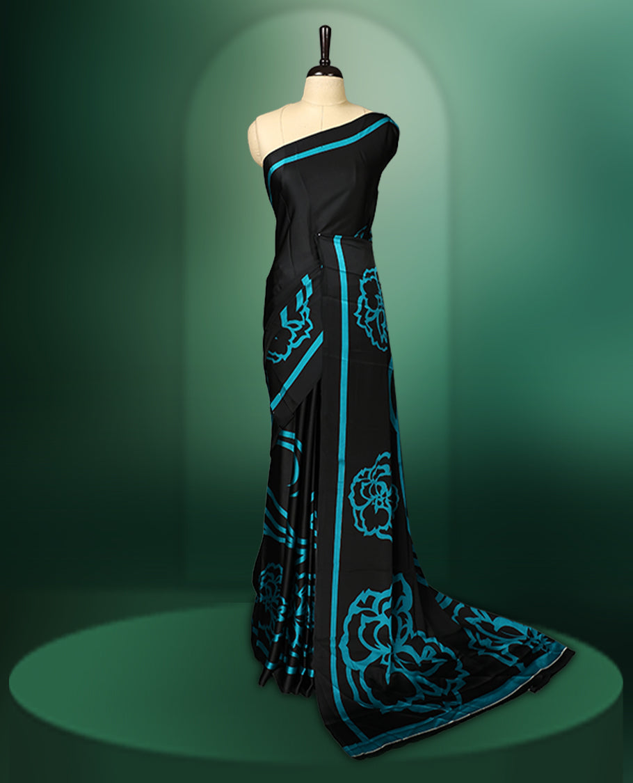 Black colour saree adorned with bold Light Blue floral motifs and matching border accents, paired with a coordinating blouse