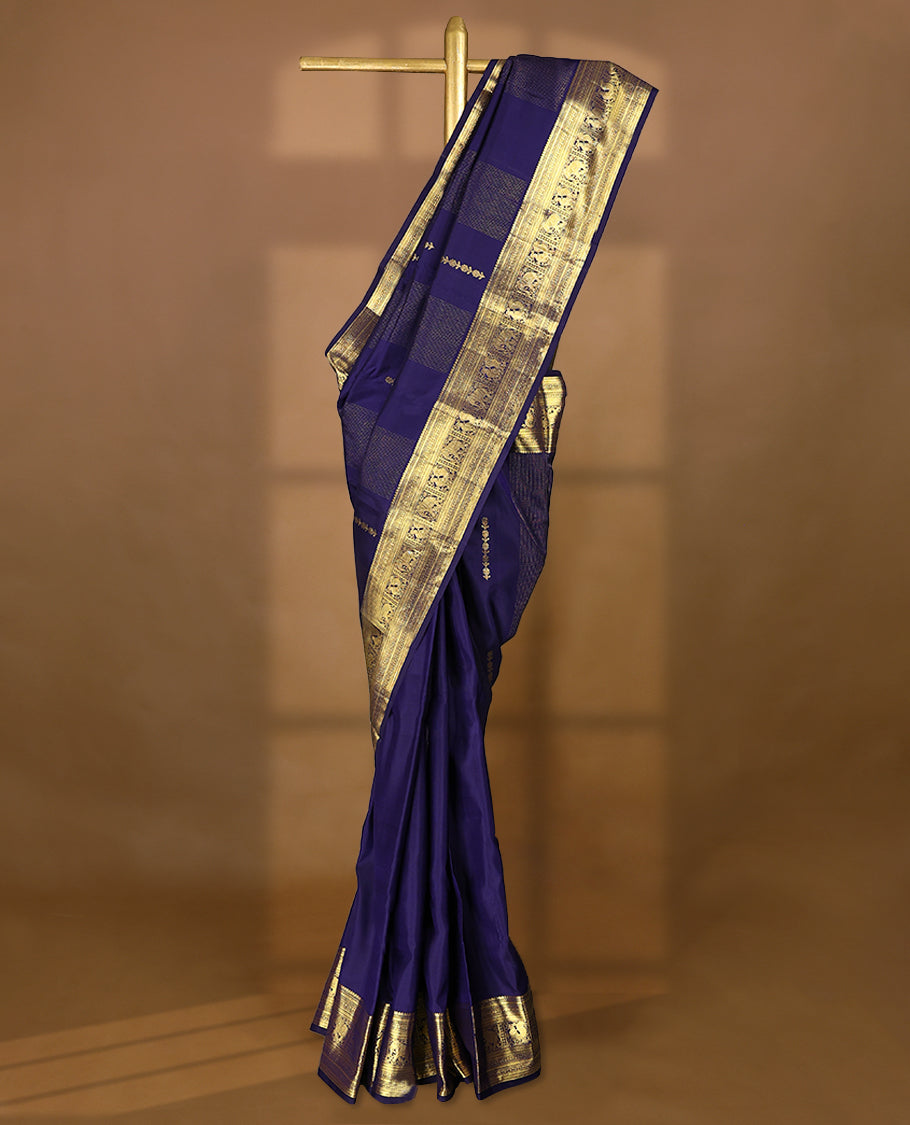 Navy blue Colour pure traditional Kancheepuram silk saree featuring antique zari line patterns on the body, complemented by a traditional border adorned with peacock and elephant motifs, and paired with a matching blouse.