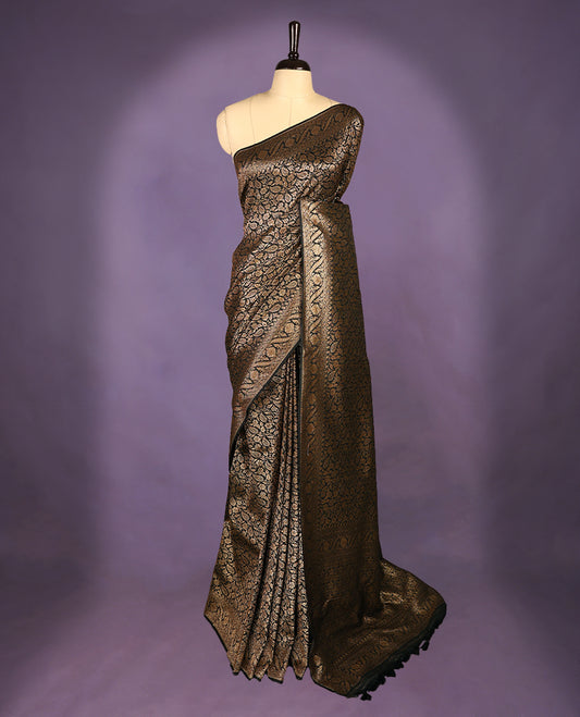 Black colour semi Banaras Katan silk saree featuring intricate Antique Bronze zari floral and vine patterns woven throughout the body, enhanced with a rich traditional border and detailed pallu, paired with a matching blouse piece.