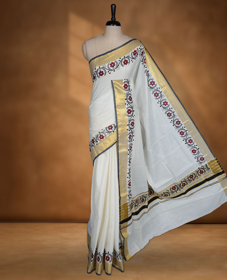 Off white colour cotton Kerala saree with floral printed borders, highlighted by a golden zari border and classic pallu, paired with a matching blouse.