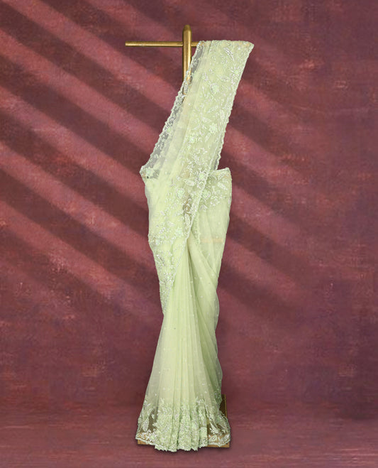Pastel pistachio green colour net designer saree embellished with delicate floral thread and sequin embroidery along the border and pallu, with subtle sequin accents on the body, paired with a matching worked blouse for a refined look