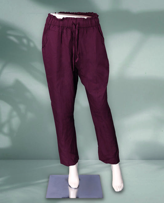 Deep plum colour women's pants feature an elasticated waistband with a drawstring, side pockets, and a relaxed ankle length fit
