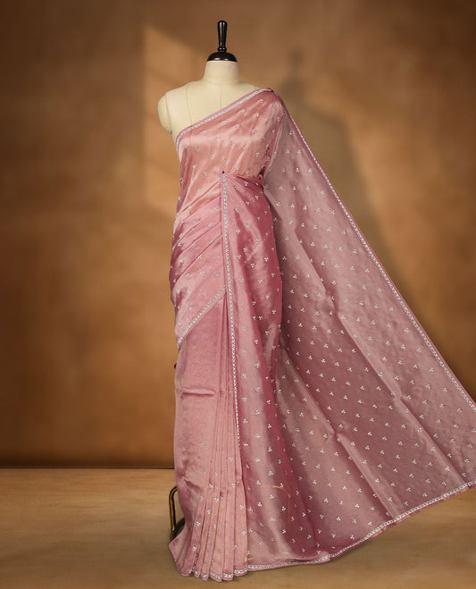 Pastel Pink Colour net shimmer fancy saree adorned with scattered white stone buttas all over the body, paired with a delicate stone worked border and matching blouse featuring floral vine stone embroidery