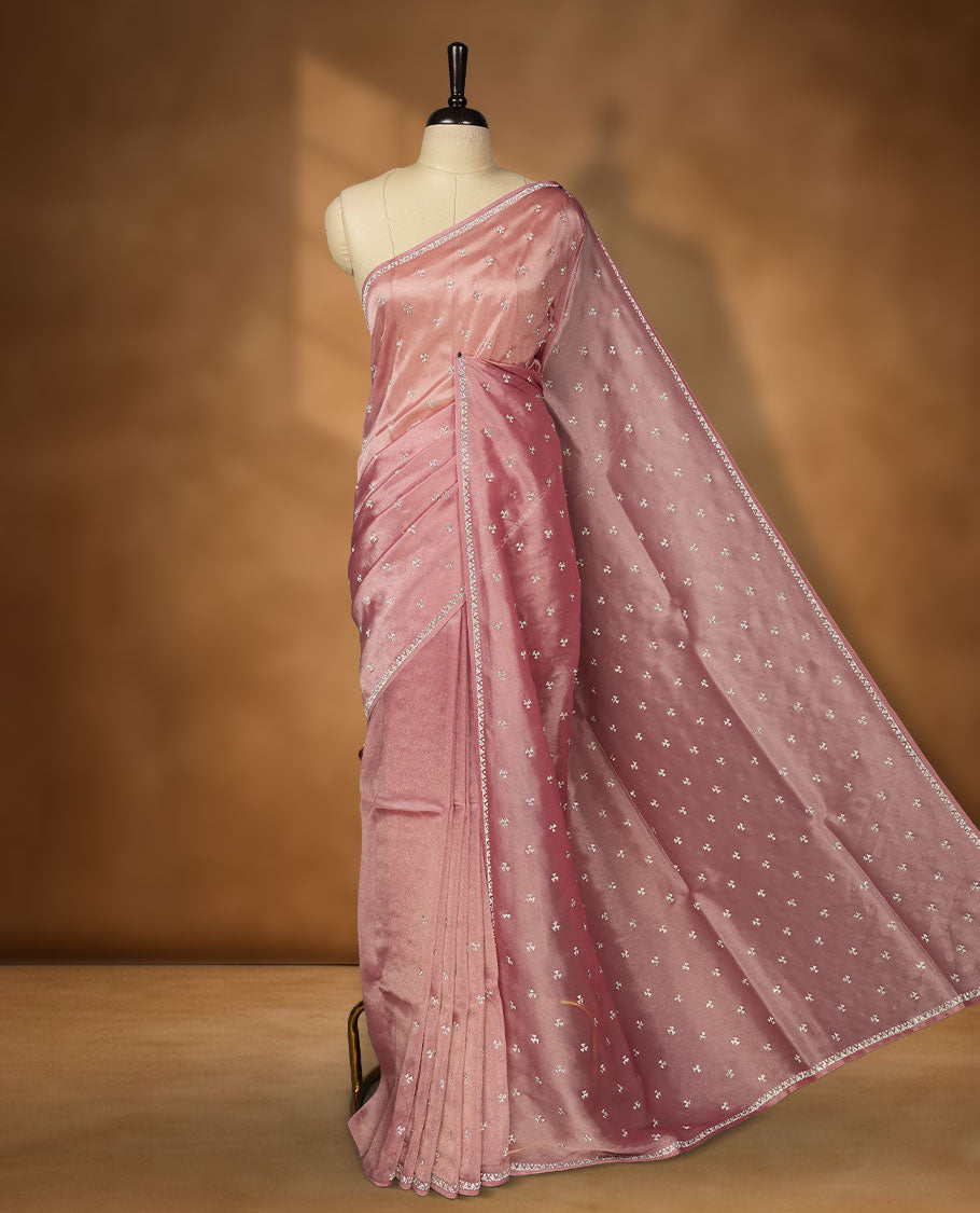 Pastel Pink Colour net shimmer fancy saree adorned with scattered white stone buttas all over the body, paired with a delicate stone worked border and matching blouse featuring floral vine stone embroidery