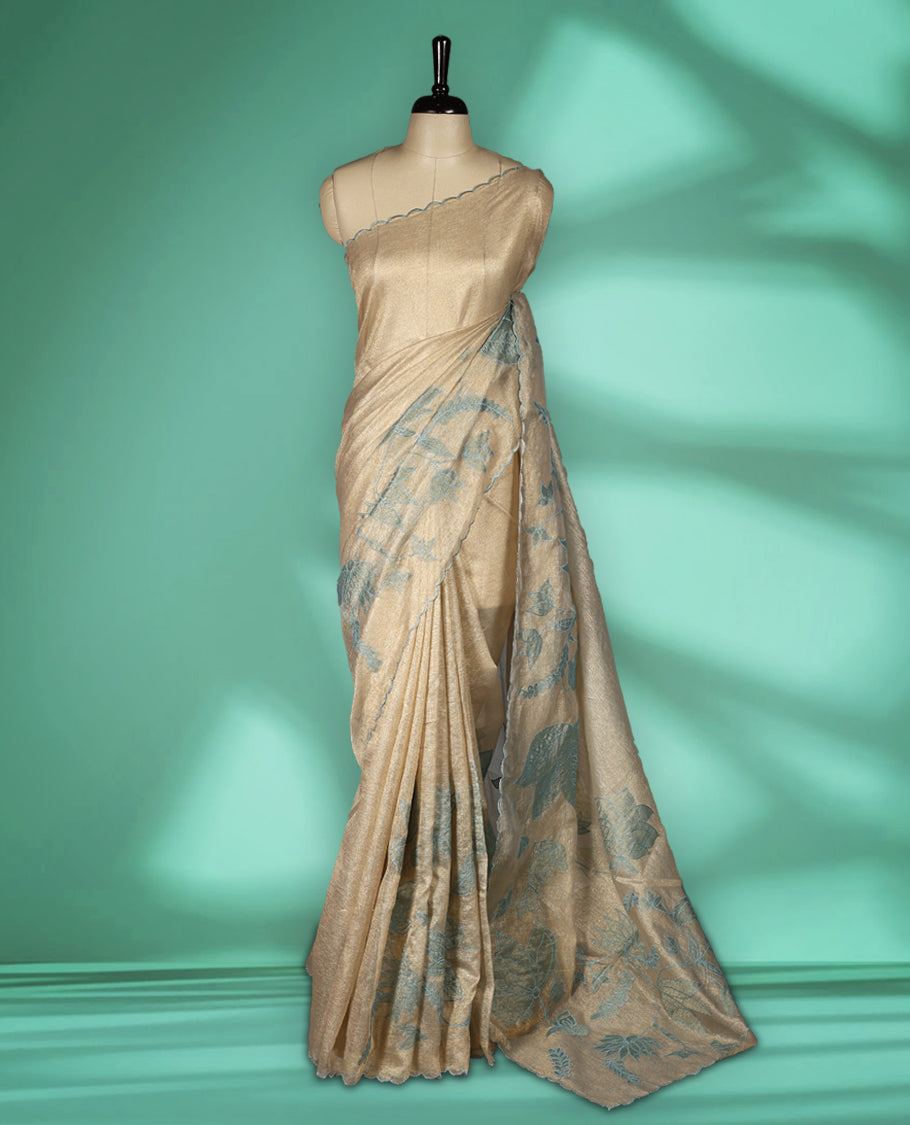 Champagne beige colour organza designer saree featuring subtle woven texture on the body, adorned with soft Blue floral embroidery along the border and pallu, finished with scalloped Thread edging paired with matching blouse.