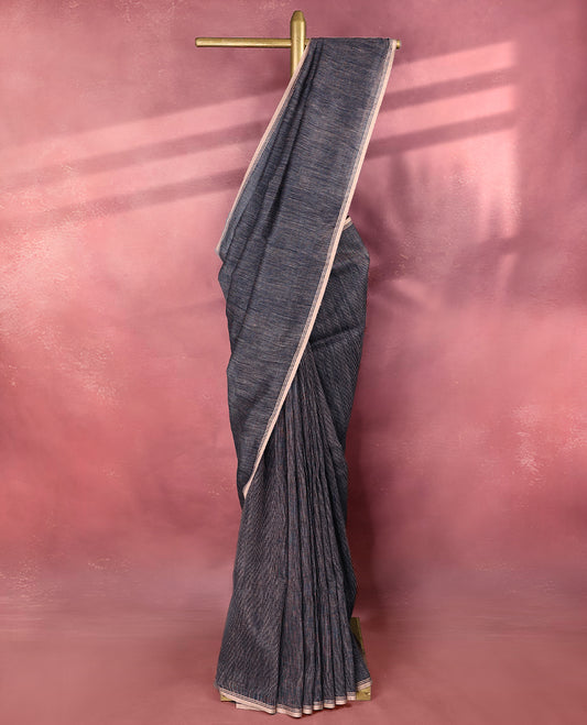 Deep navy blue colour pure linen saree featuring fine beige thread stripes running throughout the body, accented with a soft beige border and pairs gracefully with a matching blouse.
