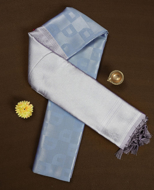 Light lavender colour semi silk saree adorned with subtle silver zari motifs on the body, complemented by a pastel light blue pallu intricately woven with rich floral patterns border and pallu, and paired with a matching blouse